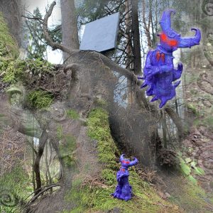 A sculpture of a small blue demon with red eyes stands by a mossy tree trunk; the demon is digitally cloned and enlarged in the upper right corner of the image