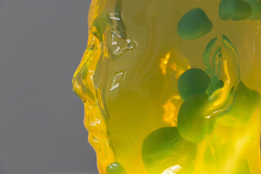 Profile view of a plastic bust holding a yellow and green lava lamp
