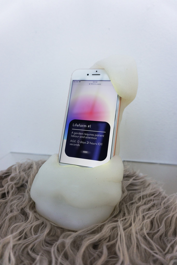 A smartphone showing a colorful orb rests in a blobby white resin