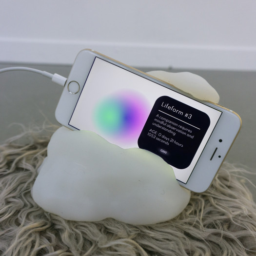 A smartphone showing a colorful orb rests in a blobby white resin