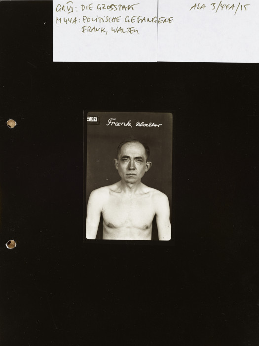A small black-and-white portrait of a shirtless middle-aged man with his name written at the top; the photo is set on a black field with archival notes handwritten on a white strip at the top