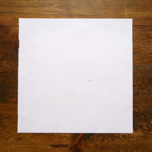 A page with one dot lies on a wooden surface
