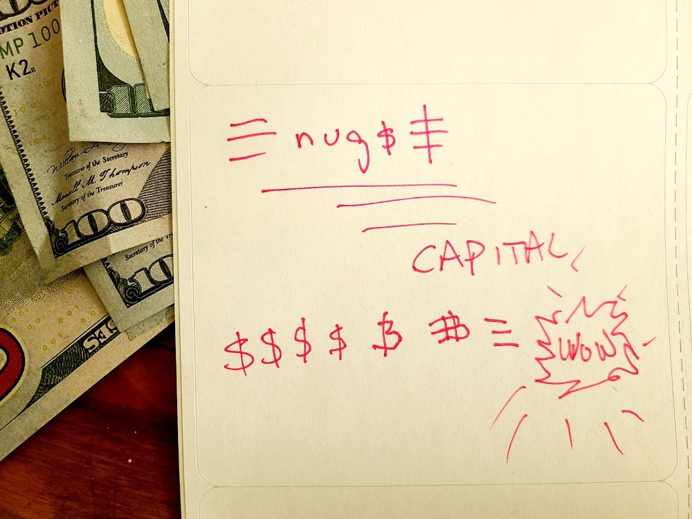 A photograph of a piece of paper with notes about money scribbled in red ink, laid over several hundred-dollar bills