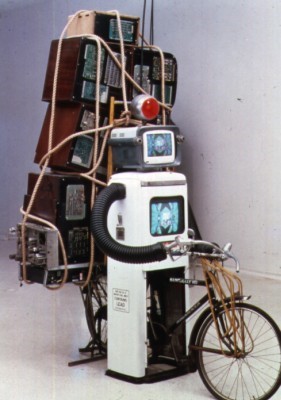 A photograph of an art work made of many television monitors tied together with rope