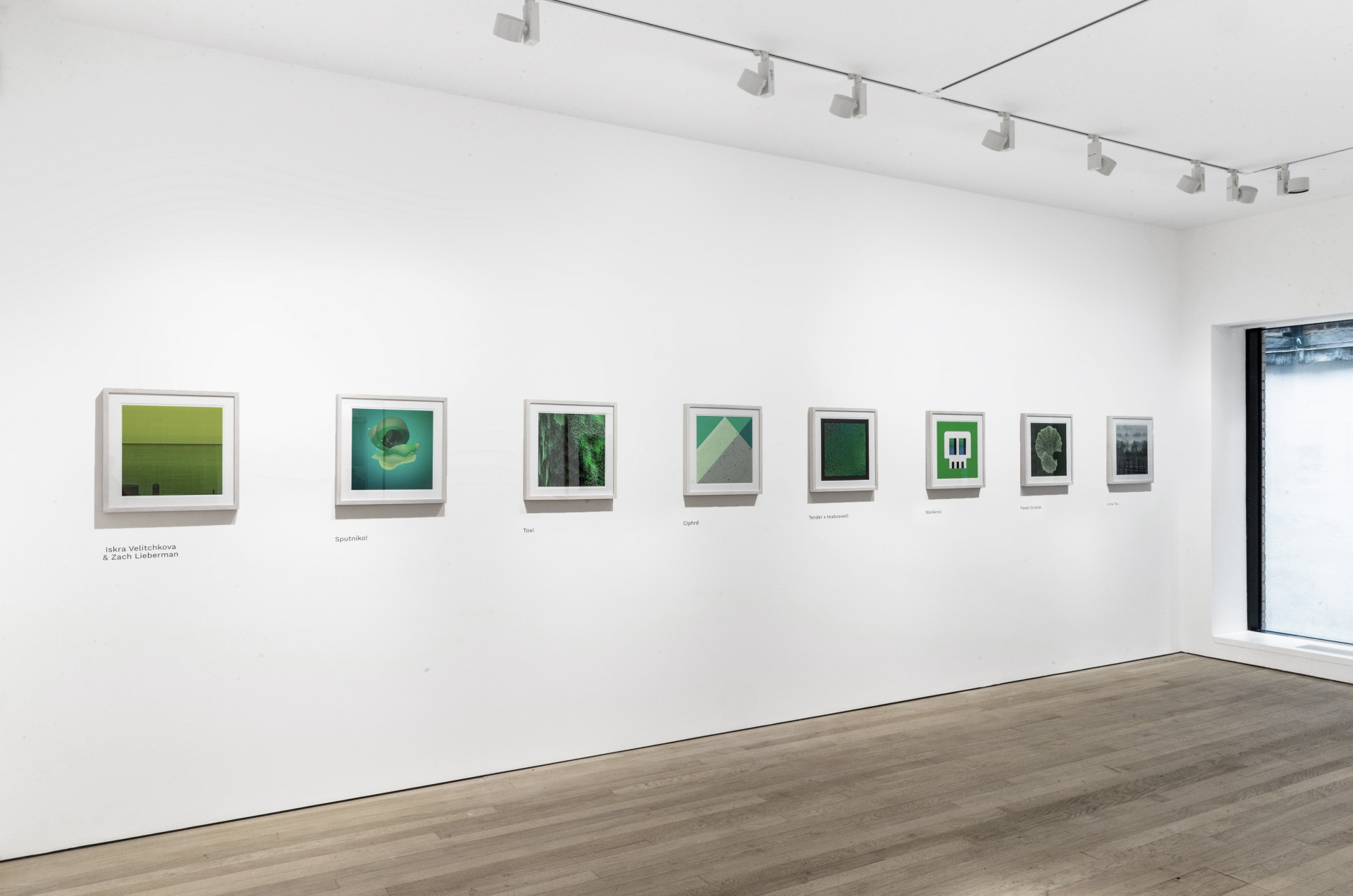 A white-cube style gallery with a row of framed square prints of NFTs, all green