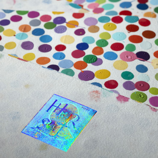 A photo of a painting on paper of multicolored dots, showing a small rectangular hologram with a man's silhouette