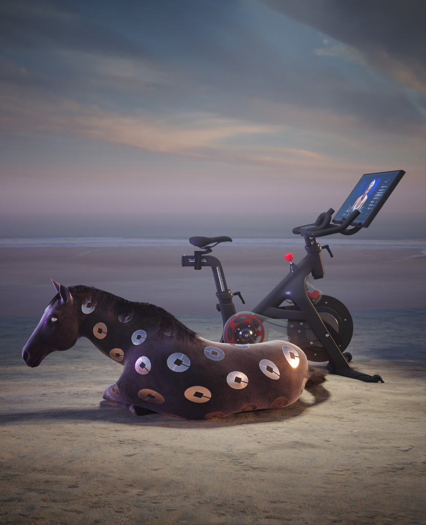 A digital image of a horse covered with Uber logos reclining on a beach at dawn beside a Peloton bike
