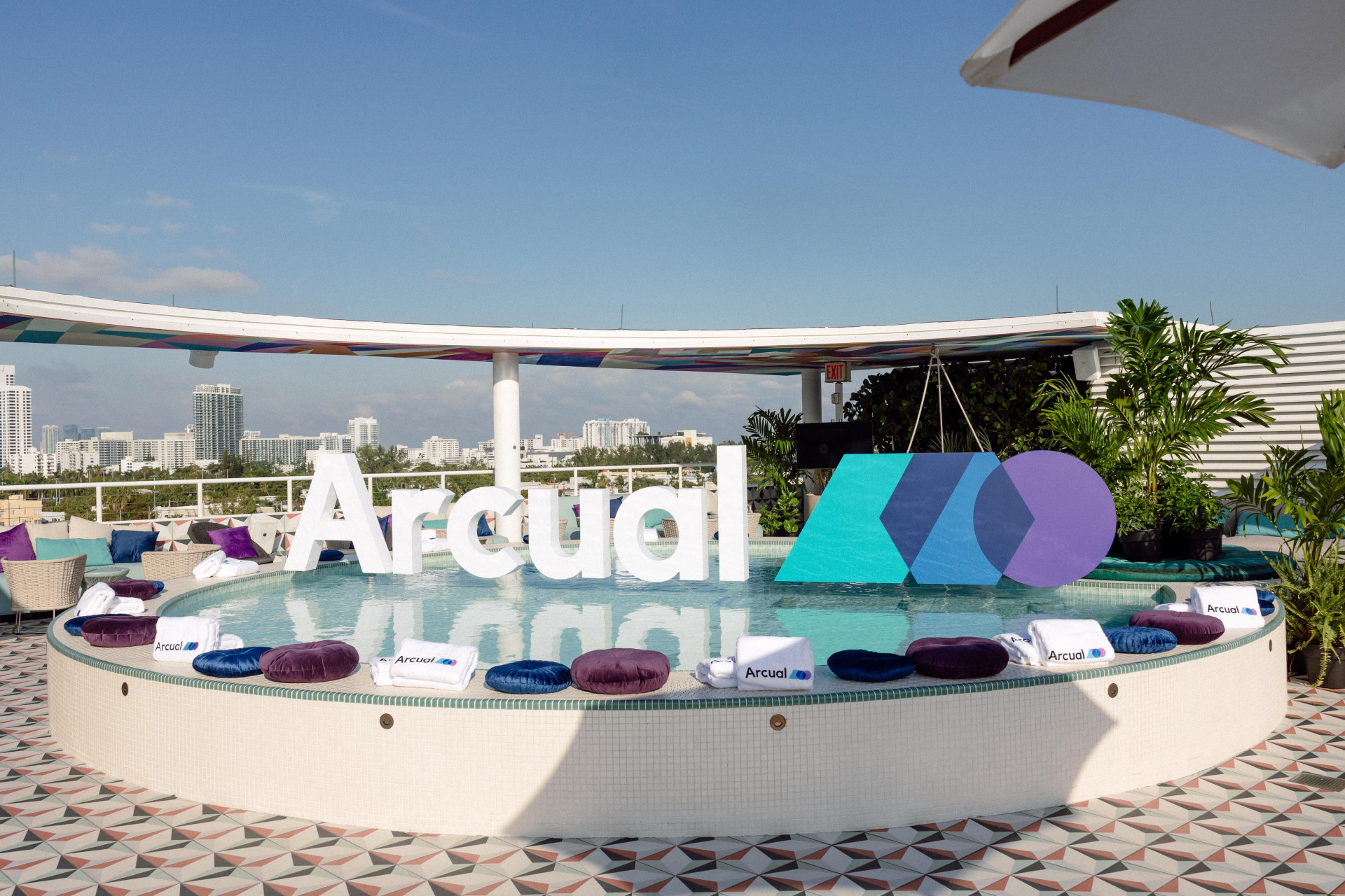 A rooftop view of a cushioned platform with the Arcual logo in the background