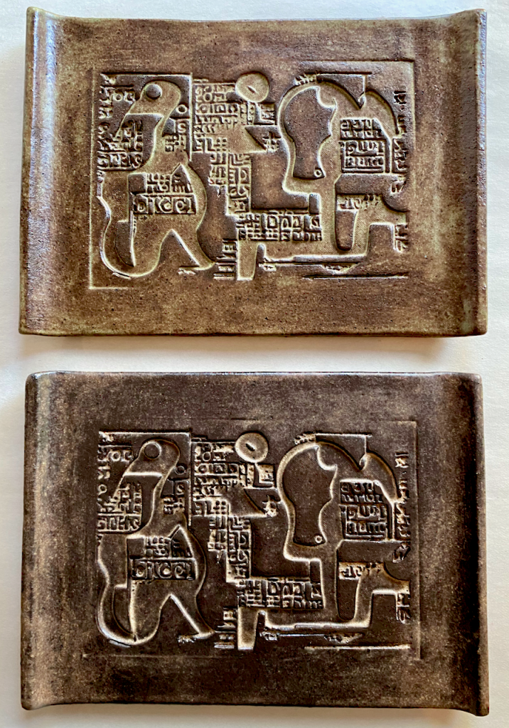 A pair of ceramic trays with abstract reliefs that recall ancient clay tablets inscribed with writing