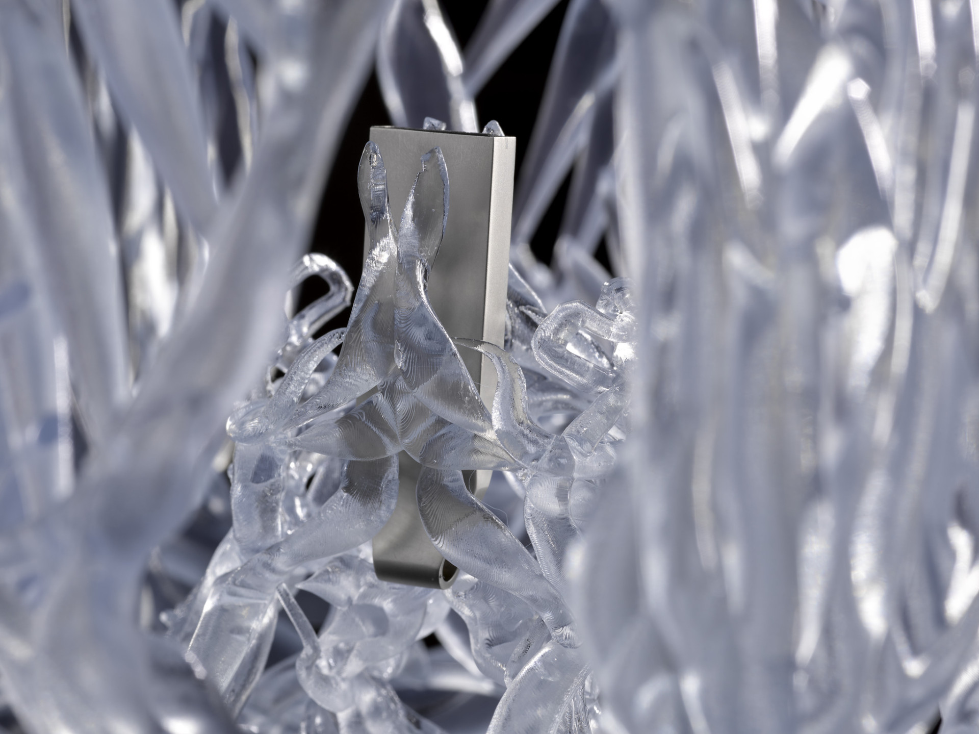 A metal memory stick encased in a tangle of white plastic semi-translucent tubes