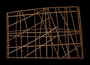A photo of a flat rectangular object made from wooden sticks and dotted with cowrie shells